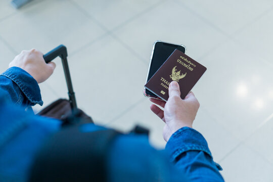 Top view hand man passenger showing passport issue and e-ticket to flight. Touris man showing passport and boarding pass on mobile phone. Businessman showing smartphone online air ticket at airport. - Powered by Adobe