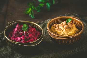 Bowls with beetroot hummus and chickpea hummus on a rustic dark wooden background