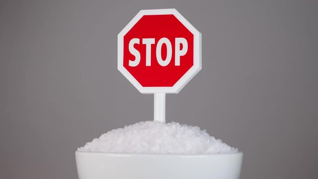 Rotation of a bowl of salt with stop sign as a concept of low sodium diet.No salty food.heart disease.heart health.Concept of healthy lifestyle.salt free diet.