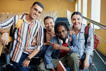 Portrait of group of happy students smiling at camera studying together at college