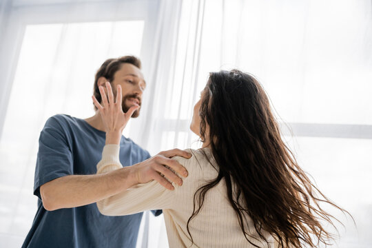 Brunette woman beating blurred boyfriend during quarrel at home.
