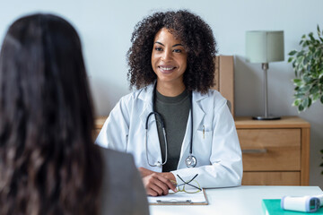 Beautiful cheerful female doctor talking while explaining medical treatment to patient in the...