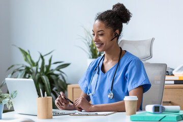 Beautiful female doctor talking with colleagues through a video call with a laptop in the...