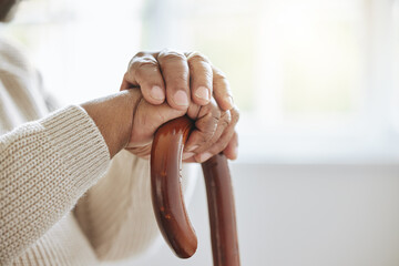 Waiting for another day. Shot of a senior man leaning in his walking stick at home.