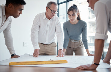 Planning ensures success. Cropped shot of four architects looking over blueprints in the office.