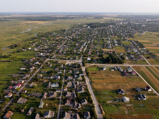 Aerial view of small village in Ukraine. Above view of rural area houses, cultivated fields and parcels, country roads. Field panorama with agricultural and roof of houses village countryside