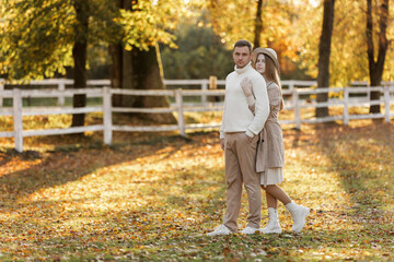Fototapeta premium Young stylish couple lovers are hugging in the autumn park. Lovely romantic moment between man and woman in love. Happy family. Love, youth, happiness concept.