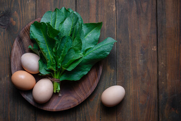 Fresh organic sorrel, spinach plant bunch on wooden table for spring green vegetables soup & salad. Raw sorrel leaves top view green vegetable background. Spring green vegetables - sorrel spinach egg.