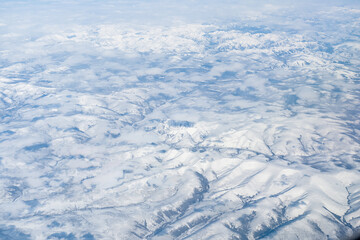 Aerial view of the Siberian hills and mountains covered with snow in the tundra. Siberia, Far East of Russia. Snow-covered tundra in the Arctic.