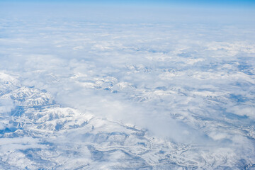 Aerial view of the Siberian hills and mountains covered with snow in the tundra. Siberia, Far East of Russia. Snow-covered tundra in the Arctic.