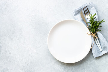 Table setting, serving on white. White plate, cutlery and napkin. Flat lay image with copy space.