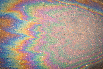 Petroleum fuel spilled on wet asphalt, abstract background.