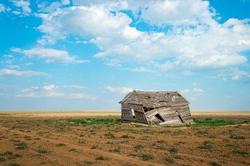 Abandoned Wooden Barn in Rural Farmland with Dirt and Patches of Grass