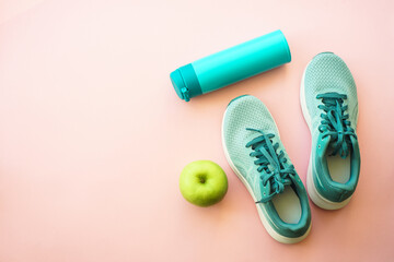 Workout and healthy lifestyle concept. Sneakers, green apple and bottle of water. Flat lay with copy space.
