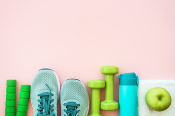 Fitness equipment on pink background, flat lay image. Sneakers, dumbbells, towel and bottle of water. Training, workout and fitness concept.