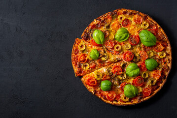 Pizza Margherita with basil tomato and mozzarella, top view on a black background .