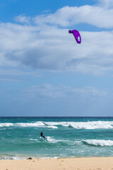 Kitesurfing. Unrecognizable man is flying on the sea wave on the board