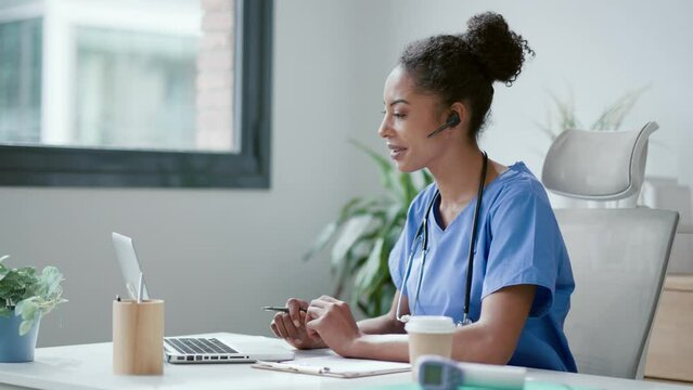 Video of beautiful female doctor talking with patient through a video call with a laptop in the consultation.