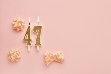 Number 47 on a pastel pink background with festive decorations. Happy birthday candles. The concept of celebrating a birthday, anniversary, important date, holiday. Copy space. banner