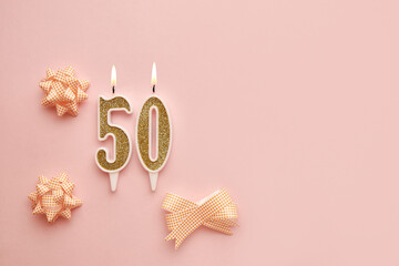 Number 50 on a pastel pink background with festive decorations. Happy birthday candles. The concept...