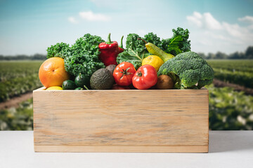 Wooden box with set of vegetables and fruits on blurred  farmer's field. Organic natural farm...