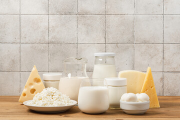 Variation of organic dairy products on wooden table. Farm cheeses, milk, cottage cheese, yogurts on beige tiles background with copy space
