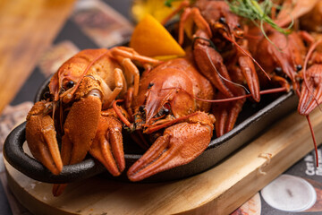 Boiled crayfish with lemon, dill and herbs on a wooden cutting board on blue wooden background. Crayfish dish