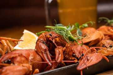 Boiled crayfish with lemon, dill and herbs on a wooden cutting board on blue wooden background. Crayfish dish