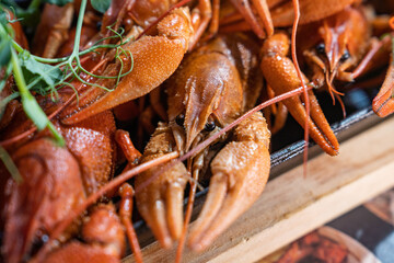 Boiled crayfish with lemon, dill and herbs on a wooden cutting board on blue wooden background. Crayfish dish