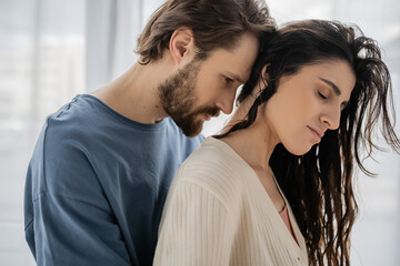 Bearded man standing near brunette girlfriend at home.