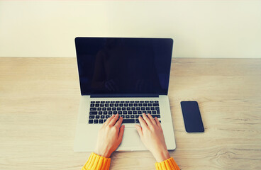 Close up woman working with laptop using smartphone on her desk in the room at home, blank black screen devices