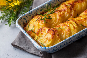 Potato gratin - graten (baked potatoes with cream and cheese) with rosemary and forks (Turkish name; Kremali patates)