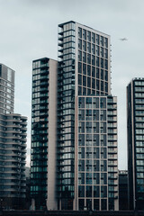 Fototapeta na wymiar Tall high-rise building in London, large block of flats, apartment buildings, modern design, blue windows, South Bank, riverside luxury property