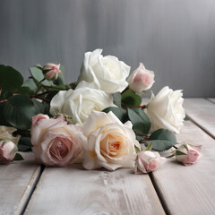 A bouquet of white and pink roses lying on a wooden table