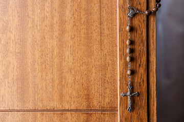 Catholic rosary hanging from wooden door