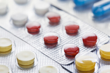 Heap of medical pills in white, blue and other colors. Pills in plastic package. Concept of healthcare and medicine.