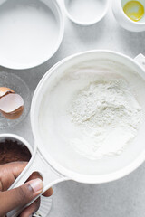 All purpose flour in a white sieve, sifting baking flour into a large bowl