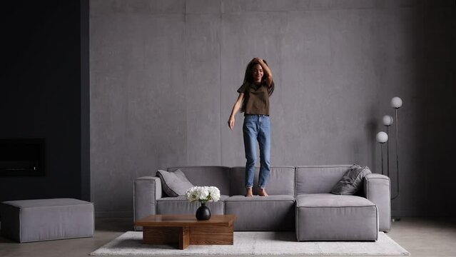 Young Woman Jumping On The Couch At Home