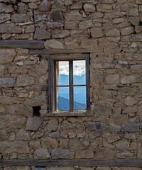 old window in the old wall seeing the beautiful snowy mountains 