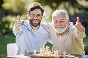 The chess life is the best life. Shot of a young and senior man playing chess together and showing thumbs up outdoors.