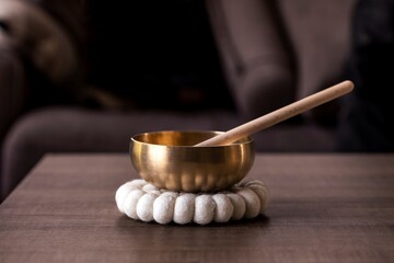 A closeup of a himalayan bowl, also called a tibetan singing bowl, with a mallet standing in it to...