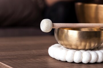A close portrait of a tibetan singing bowl or himalayan bowl, with a mallet lying on top of it to...