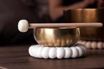 A close portrait of a tibetan singing bowl or himalayan bowl, with a mallet lying on top of it to...