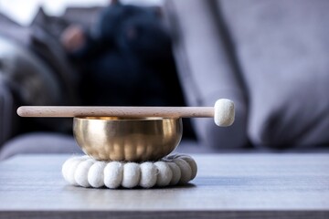 A portrait of a himalayan bowl or tibetan singing bowl, with a mallet lying on top of it to make a...