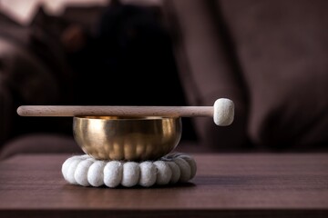 A close up of a himalayan bowl or tibetan singing bowl, with a mallet lying on top of it to make a...