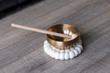 A portrait of a tibetan singing bowl, also called a himalayan bowl, with a mallet standing in it to...