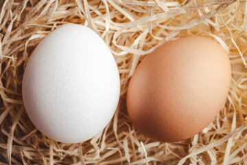Whole chicken eggs on straw. Top view.