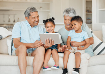 Family is not an important thing. Its everything. Shot of grandparents bonding with their grandchildren and using a digital tablet on a sofa at home.