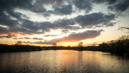 Sunset with dark clouds with reflection in a lake