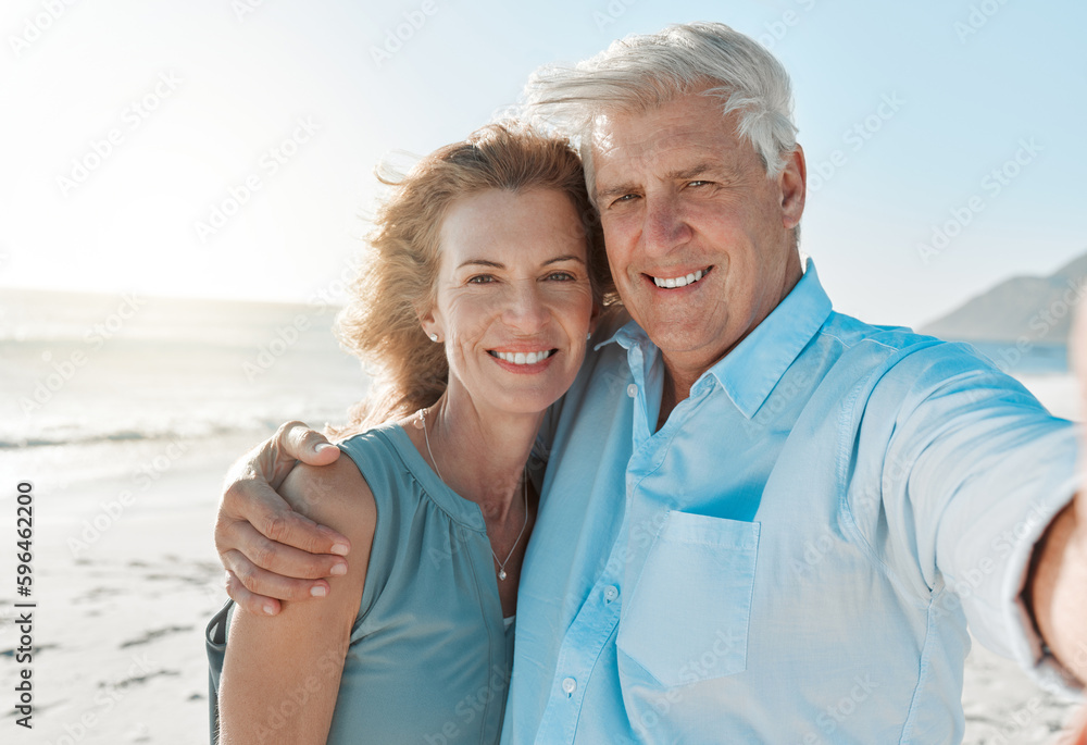 Poster im always having fun with you by my side. shot of a mature couple taking a selfie on the beach.